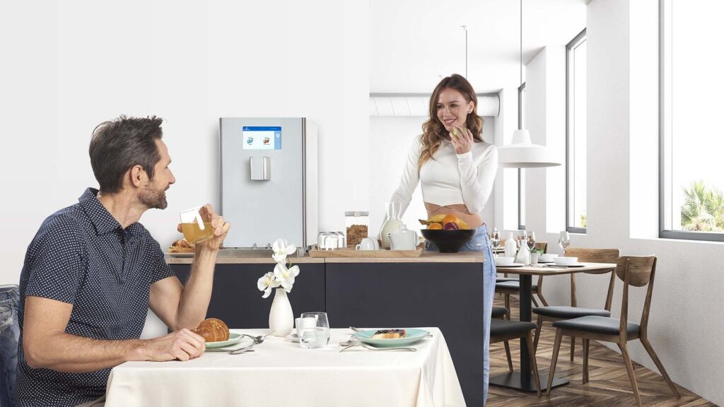Gäste am Tisch, Wasser- und Saftspender im Frühstücksraum